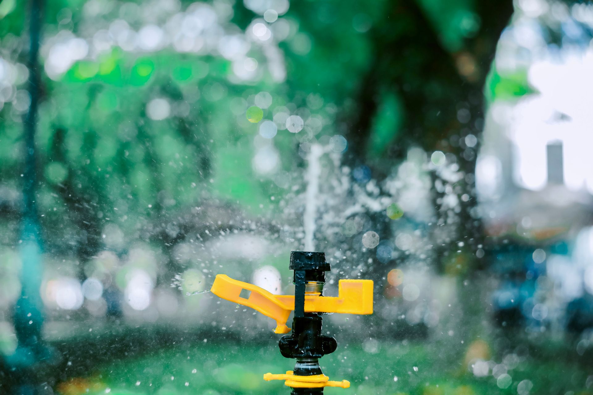 Close-up of a yellow garden sprinkler with blurred background creating a bokeh effect.